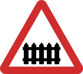 Avertissement pour un passage à niveau avec barrières.