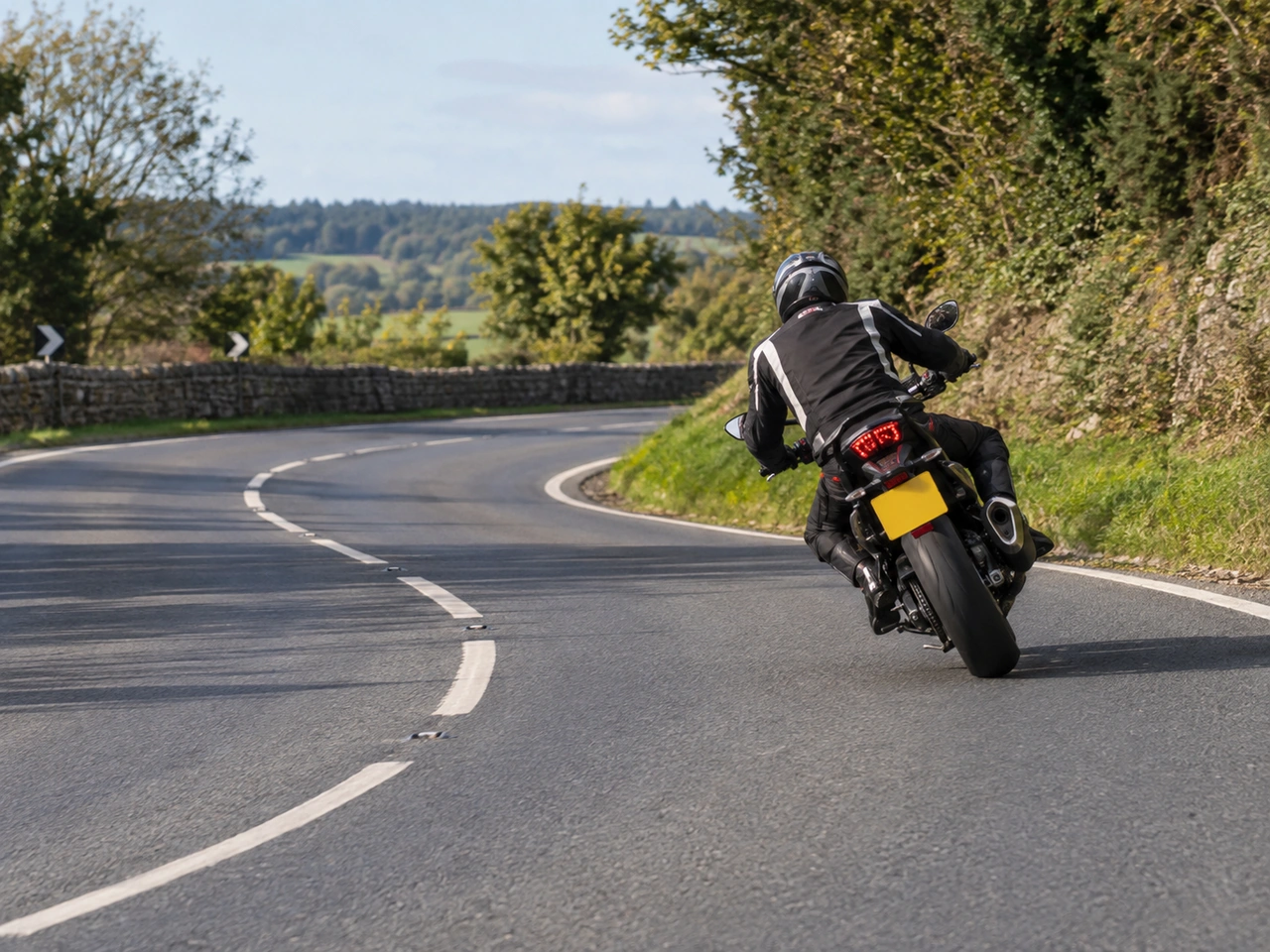 Why should hard braking be avoided while a motorcycle is leaning in a bend?