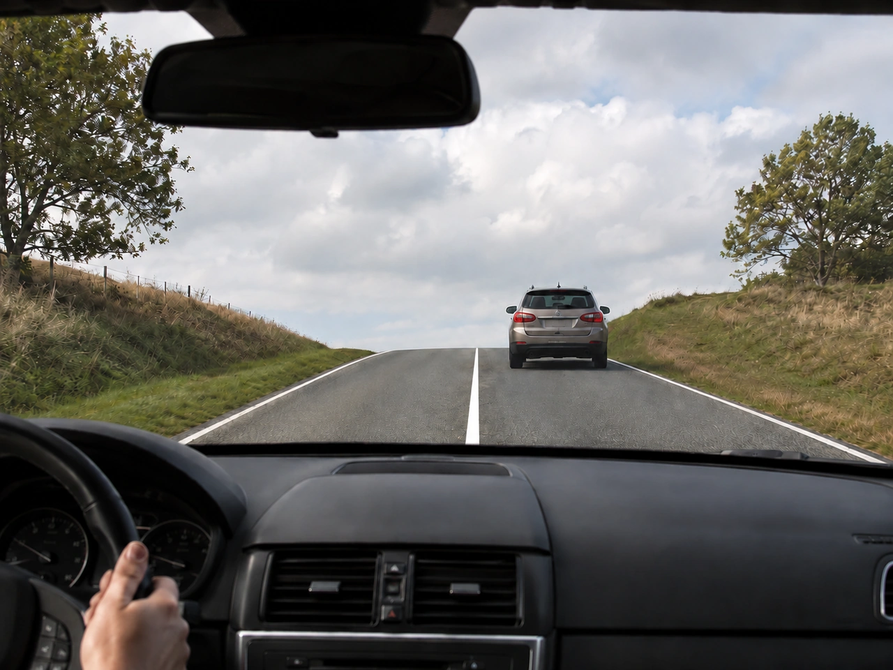 Why should you not overtake near the top of a hill?